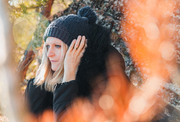 Portrait of beauty young blonde hair woman holding winter hat, jacket on stone background