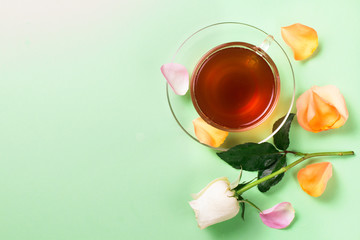 Cup of morning tea and roses on a green background..Rose petals.