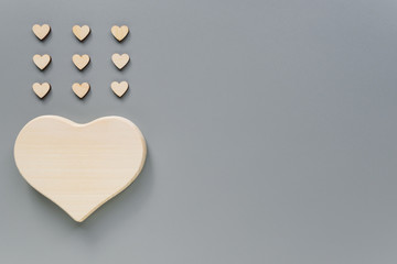 Fototapeta premium Mock-up of a wooden big heart and small hearts for Valentine's day. Hearts in the form of rain. Wooden hearts on a grey background with Kopi space