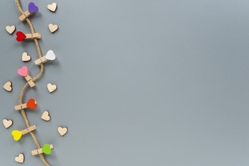 Colorful clothespins in the form of hearts on a rope. Decoration for Valentine's day. Decorative clothespins on a gray background