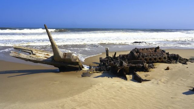 Shipwreck in the sand washed by Atlantic Ocean waves in the Skeleton Coast National Park in Namibia, Africa.