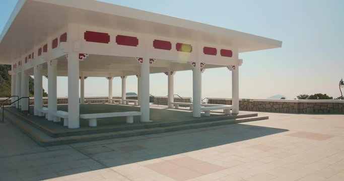 Dolly shot from a chinese pavilion built on the site of the former Mountain Lodge in Hong Kong. Beautiful sunny day & shadows. Victoria Peak Gardens. Cinematic High Dynamic Rance.