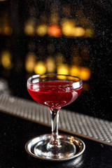 A drink in a cocktail glass with tiny drops of oil around