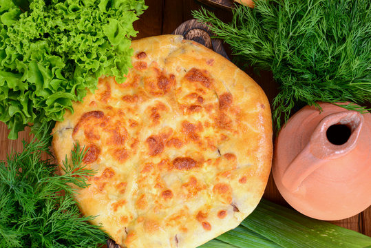 Traditional Georgian Kolkh khachapuri with suluguni and brynza cheese on the table. Khachapuri Megruli. Homemade baking.