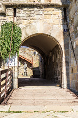 Entrance Bridge of the museum of the castello di san giusto with a tunnel and a drawbridge. In the background is a statue.