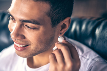 Young guy wearing a white wireless earpiece.