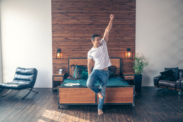 Barefoot smiling guy is standing right with his hand up.