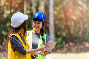 Fototapeta premium The supervisors are constructing roads in the forest. Young Engineer female holding blueprint on hand. Engineer team working on project at the forest. Technical operaters and Labourers.