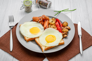 Set for breakfast fried eggs, grilled vegetables, sausages. Bread on a wooden table.