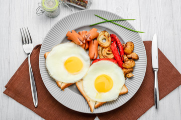 Set for breakfast fried eggs, grilled vegetables, sausages. Bread on a wooden table.
