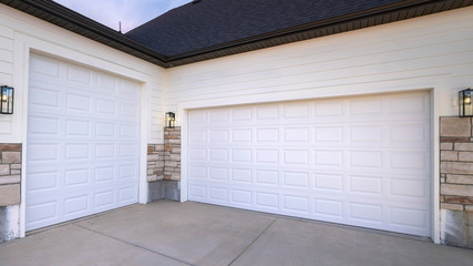 Panorama frame Two garage doors sharing a paved forecourt - obrazy, fototapety, plakaty