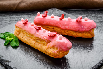 Traditional French dessert. Eclair with chocolate icing and raspberries.