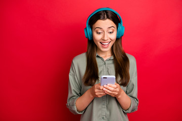 Close-up portrait of her she nice attractive lovely glad cheerful cheery straight-haired girl in khaki shirt choosing listening track hit isolated on bright vivid shine vibrant red color background