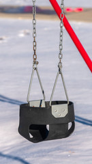 Vertical Close up on a kids swing in winter snow