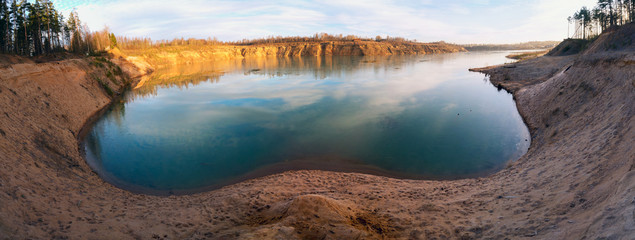 Mirror image in the water on the shore of a sand quarry. Leningrad region. Russia.Panorama.