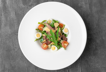 Salad with beef tongue and arugula. On a large white plate. View from above. Gray concrete background.