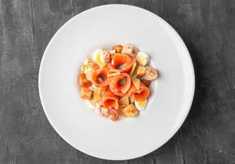 Caesar salad with salmon. On a large white plate. View from above. Gray concrete background.