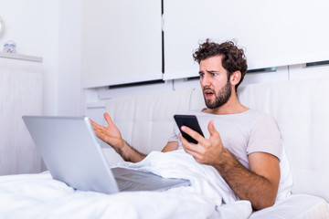 Furious man in bed angry about bad news online or pc software failure, mad helpless man having...