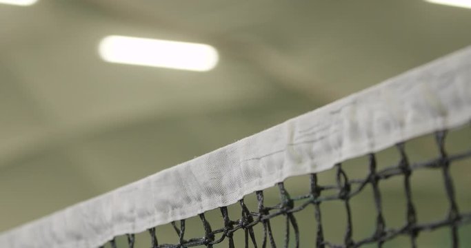 Netball in tennis tournament, indoor court, tennis player hits the ball into the net, a bad shot, slow motion.