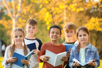 Cute little children reading books in park