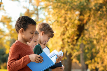 Cute little children reading books in park