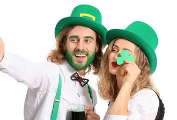 Young couple taking selfie on white background. St. Patrick's Day celebration