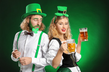 Young couple with beer on color background. St. Patrick's Day celebration