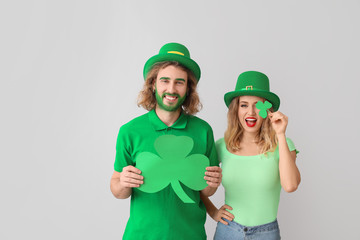 Young couple with shamrock on light background. St. Patrick's Day celebration