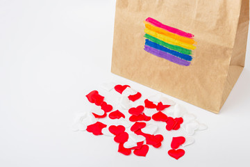 LGBT rainbow flag painted on a paper gift bag. Concept of LGBT and human rights. Many fabric hearts spilling out of the package. Gift for valentines day concept. Copy spase for text.