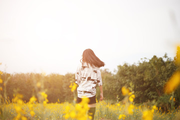 Young asian woman flick her hairs with embracing a yellow flower fields