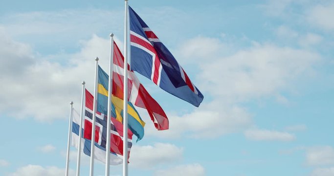 Zoom out shot of scandinavian union flags, swedish, danish, norwegian and icelandic flapping in wind on sunny summer day. Northern countrie in economic cooperation