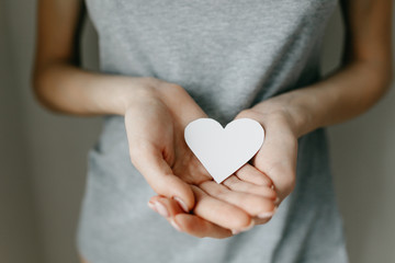 Obraz premium Gray t-shirt on the girl. Paper white heart, medicine. A heart from a woman's crossed arms.