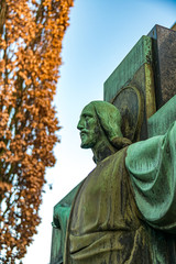 große Jesusstatue neben einem Baum im Herbst
