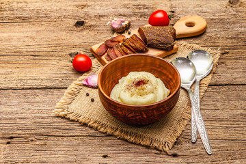 Homemade Thanksgiving garlic mashed potatoes with fresh tomatoes and pastrami. Sackcloth napkin, spoons, old wooden boards background