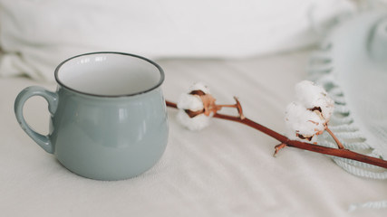 Obraz na płótnie Canvas Coffee cup and cotton twig. Breakfast in bed. Cozy home. flat lay, still life.