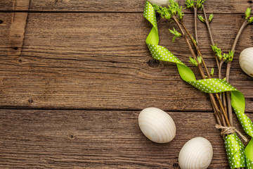 Zero waste Easter concept. Spring twigs with fresh green leaves, wooden eggs, polka dot ribbon. Old vintage wooden boards background