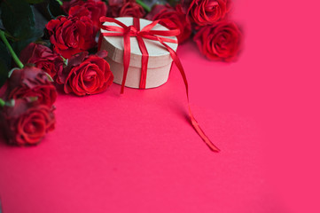 Bouquet of red roses and a craft box with a red ribbon on wooden background. Birthday. Valentine's day. March 8. Mother's day. Greeting card. Wallpaper. Banner.