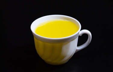 yellow liquid in a white cup on a dark background
