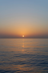 Sunset across calm water as the sun starts to dip over the horizon as a Vessel transits through the Bay of Benin in West Africa,