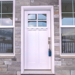 Square frame White entrance door to a house flanked by windows