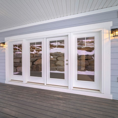 Square Wooden deck of a covered porch with large windows