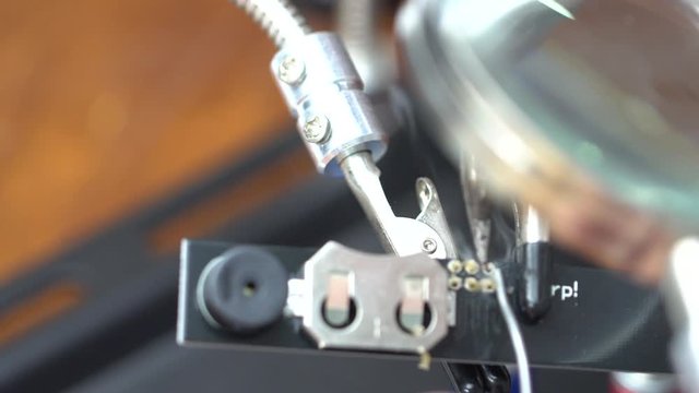 soldering the electronic circuit board footage, focused on soldering position, smake and melting lead is on the scene.