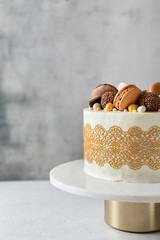 Delicious birthday cake filled with mascarpone cream and decorated with golden lace, candies,...