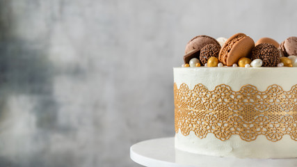 Chocolate cake decorated with candies and macaroons on dark background. Copy space, close up. Bakery, confectionery banner.