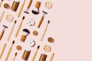 Zero waste concept. Natural bamboo toothbrush, bamboo ear sticks, razor, paper tube, wooden drinking tube, natural sponge on pink background.