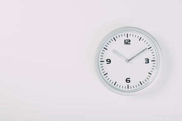 White wall clock with a yellow used hanging on the wall. Minimalist image of a wall clock on a light gray background with copy space