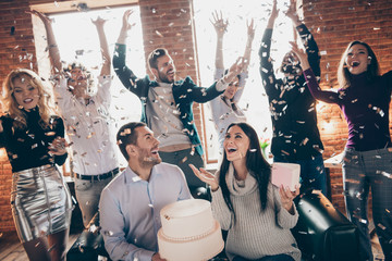 Photo of celebrating best friends arranging unexpected surprise baby party future parents sit sofa hold big cake confetti fall wear formalwear restaurant indoors