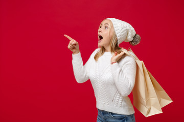Amazed woman in sweater hat isolated on red background. Healthy fashion lifestyle, cold season...