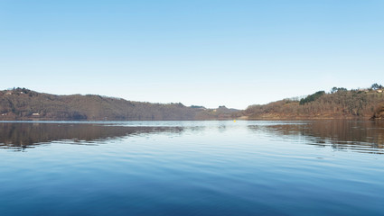 Vue sur les eaux calmes du grand lac de Bort-les-Orgues et ses berges au bord de la Commune de Lanobre