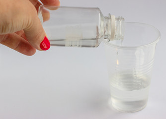 Hand pouring liquid into a plastic cup making toys called slime.